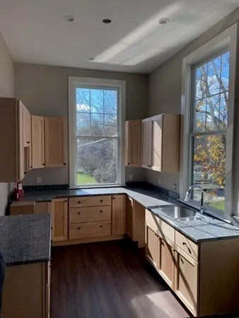 a kitchen with granite countertop a sink a stove and cabinets