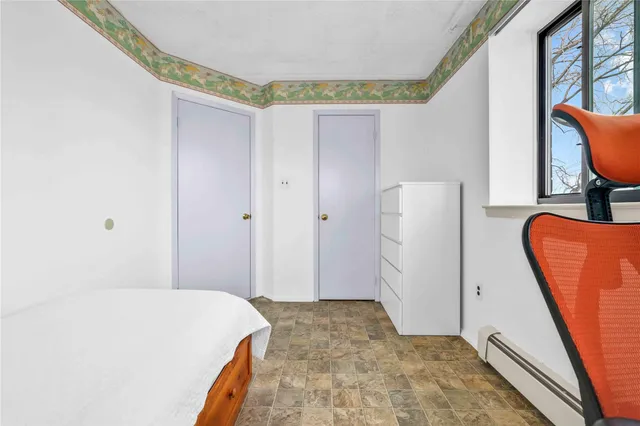 a bedroom with a bed and a chair with the wooden floor