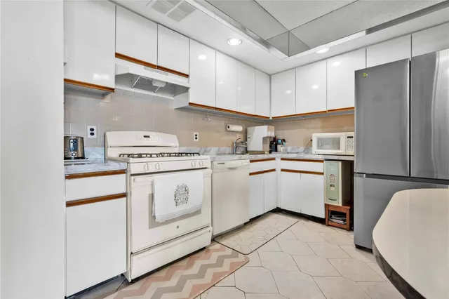 a kitchen with white cabinets and white appliances