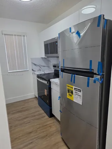 a view of kitchen with stainless steel appliances cabinets and wooden floor