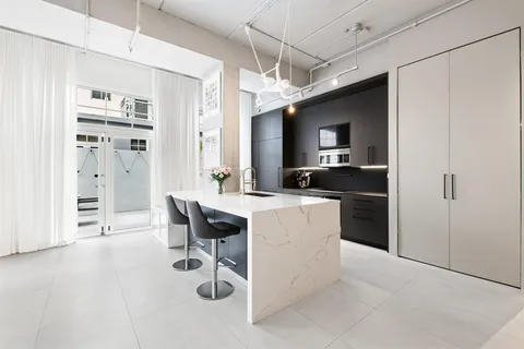 a kitchen with kitchen island a counter top space a sink stainless steel appliances and cabinets