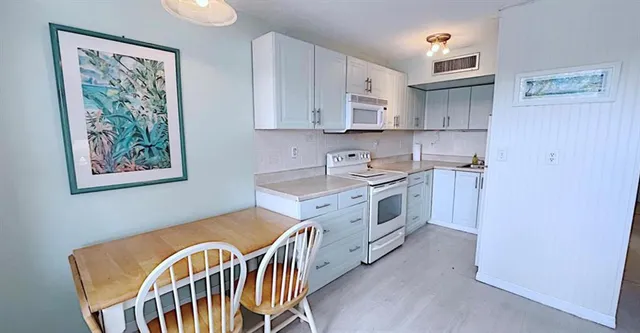 a view of a kitchen that has a lot of cabinets and wooden floor