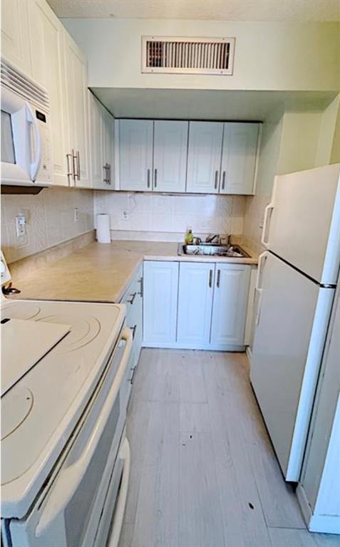 1200 Colonnades Drive, Unit 208 Fort Pierce, FL 34949 - Photo 14 of 31 a kitchen with a sink a refrigerator and cabinets