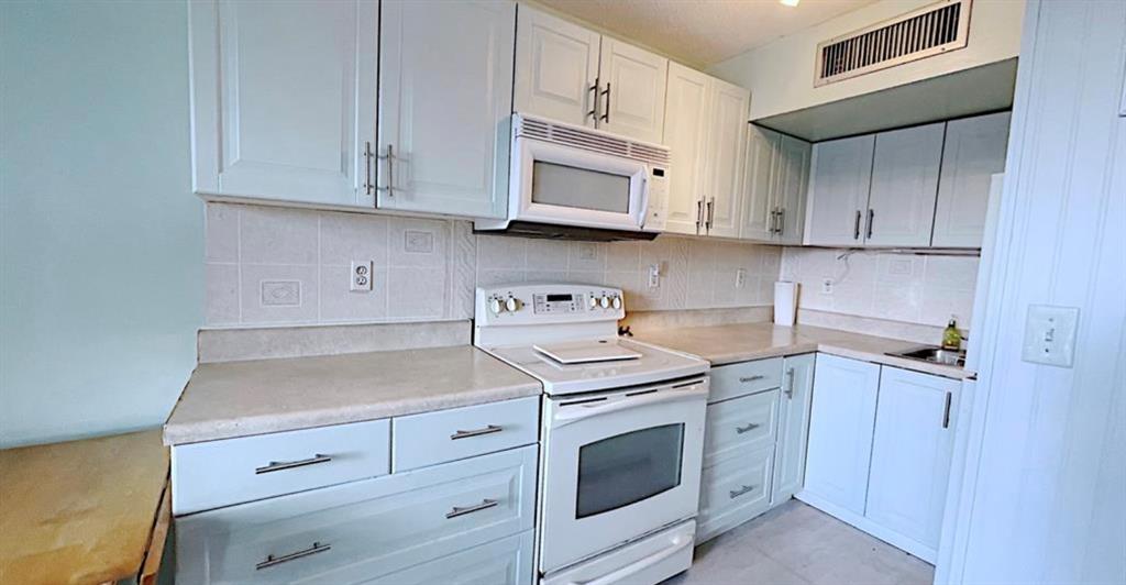 1200 Colonnades Drive, Unit 208 Fort Pierce, FL 34949 - Photo 10 of 31 a kitchen with stainless steel appliances granite countertop white cabinets and a stove top oven