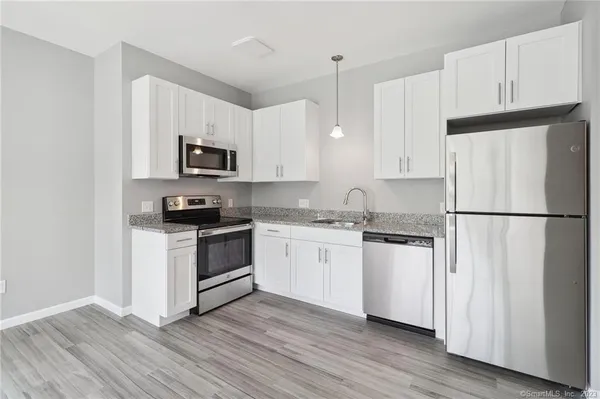 a kitchen with cabinets stainless steel appliances and wooden floor