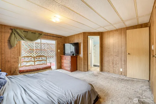 a bedroom with a bed dresser and a large window