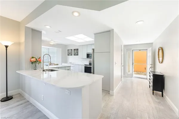 a large white kitchen with wooden floor