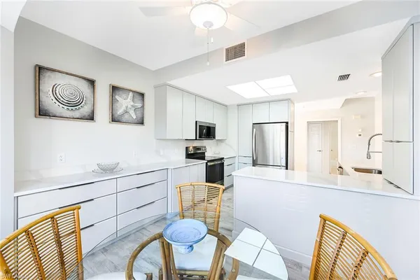 a kitchen with stainless steel appliances kitchen island granite countertop a refrigerator a stove a sink dishwasher and white cabinets with wooden floor