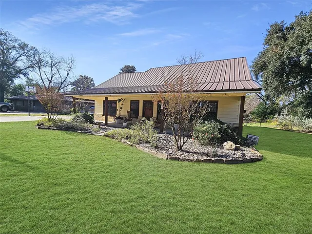 a front view of a house with a garden and trees