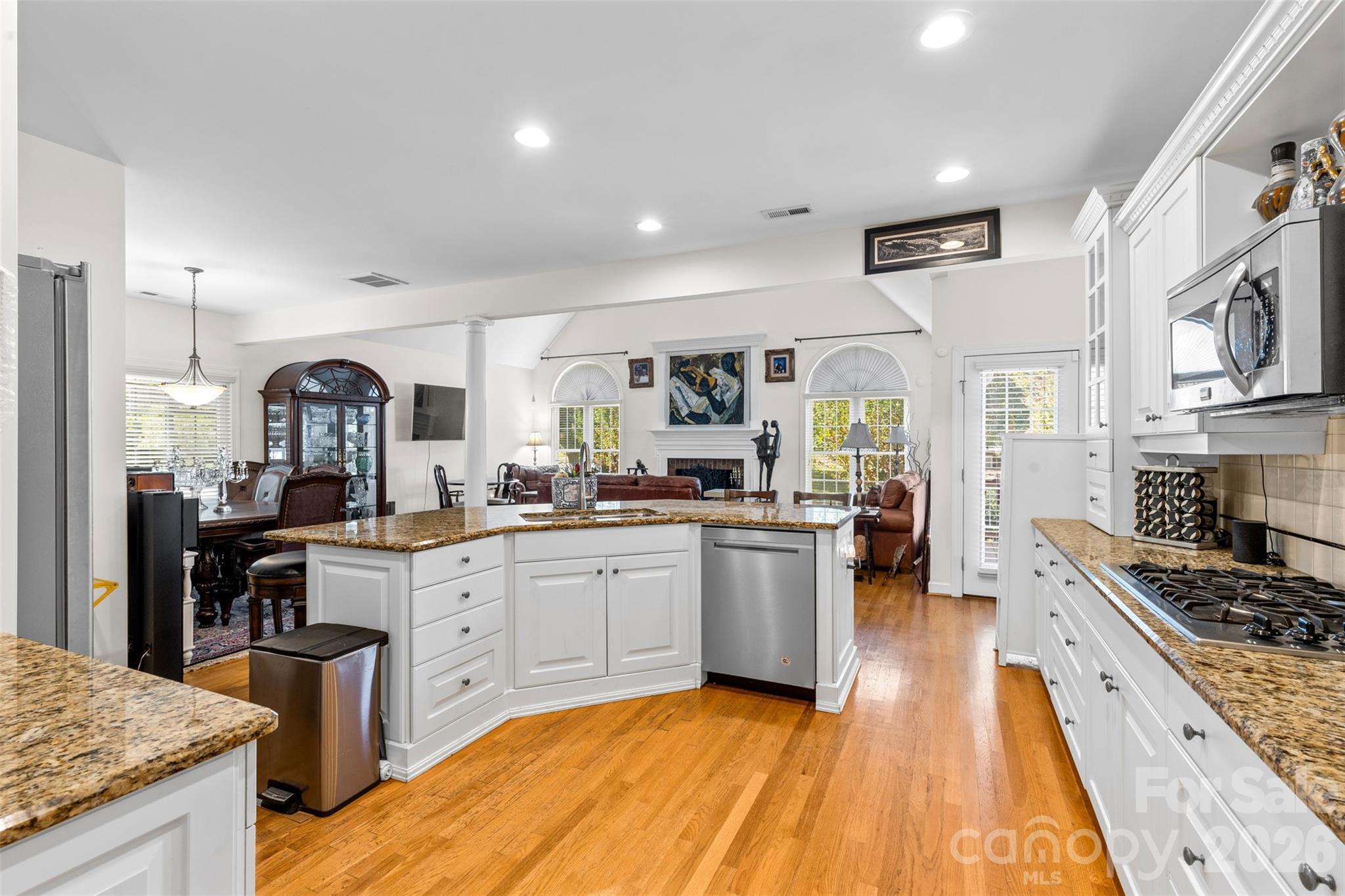 1337 Braeburn Road Northwest Concord, NC 28027 - Photo 10 of 36 a large kitchen with stainless steel appliances granite countertop a stove top oven a sink dishwasher a dining table and chairs with wooden floor