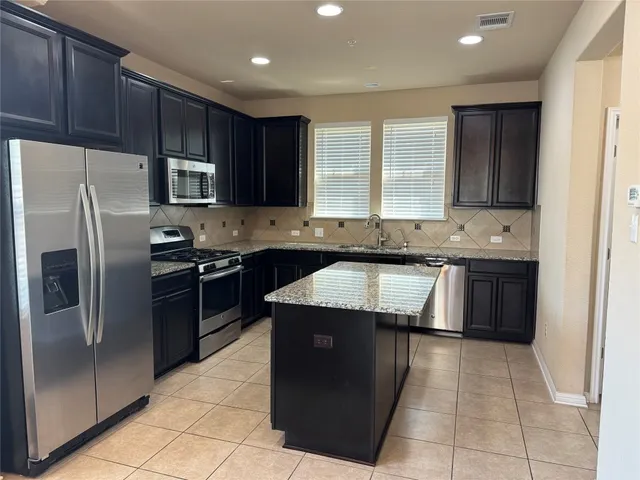 a kitchen with stainless steel appliances granite countertop a sink stove and refrigerator