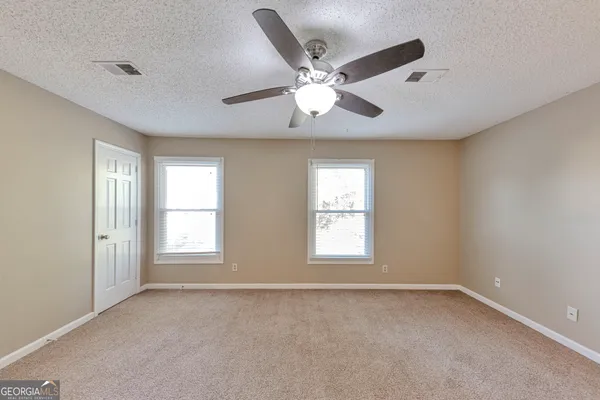 a view of an empty room with chandelier fan and fire place