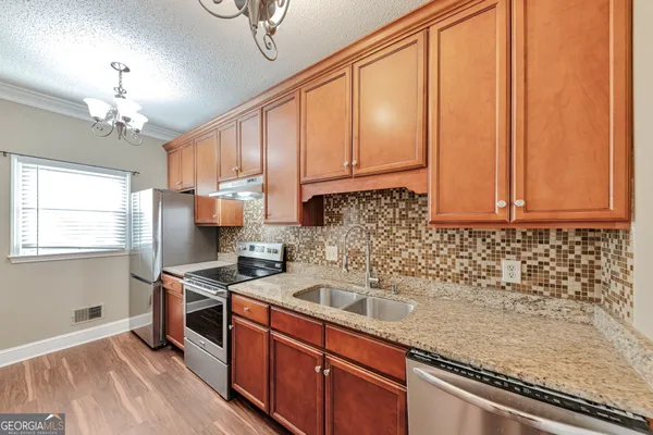 a kitchen with stainless steel appliances granite countertop a sink a stove cabinets and wooden floor