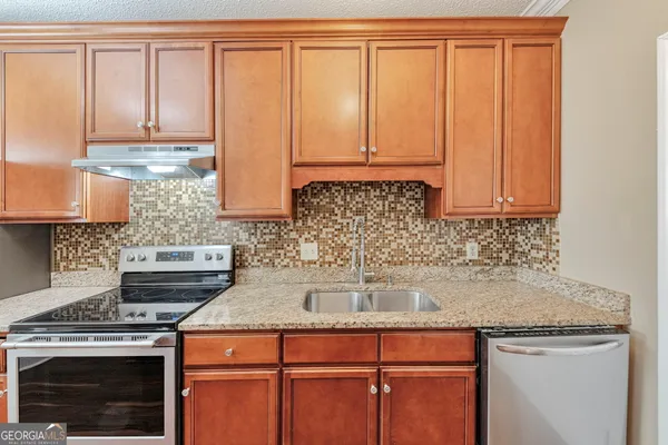 a kitchen with granite countertop a sink stove and cabinets