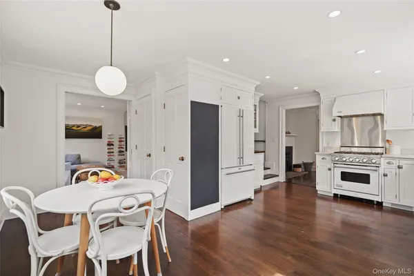a open kitchen with stainless steel appliances granite countertop a stove refrigerator and a dining table with wooden floor