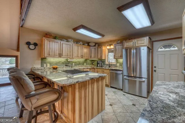 a kitchen with stainless steel appliances granite countertop a stove a sink and a refrigerator