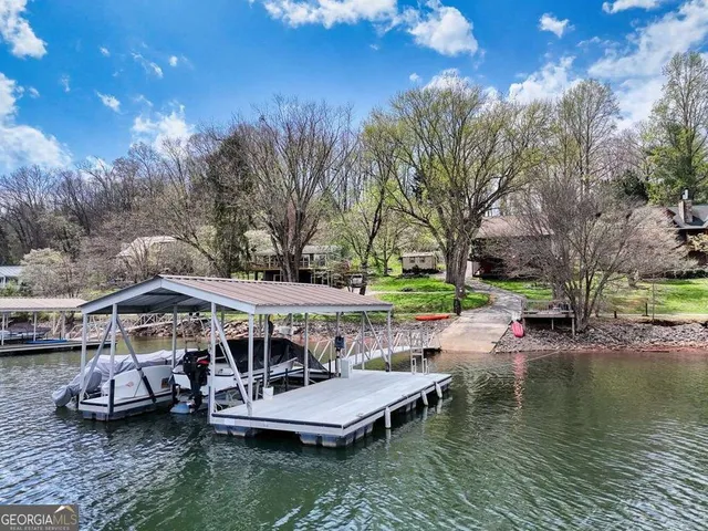 a view of a lake with lawn chairs under an umbrella