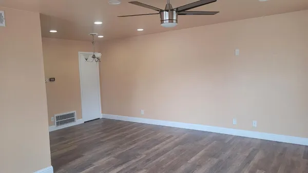 an empty room with wooden floor and fan