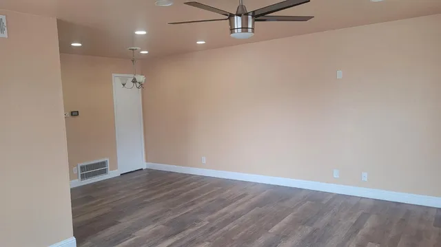 an empty room with wooden floor and fan