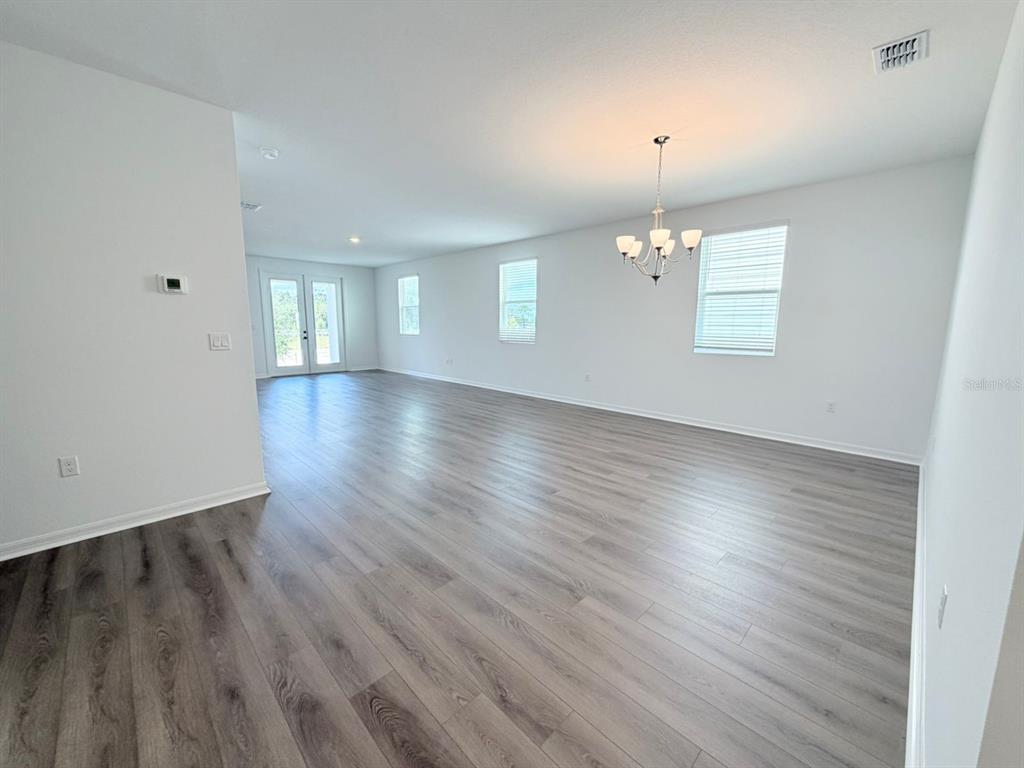 30155 Rustic Mill St Mount Mount Dora, FL 32757 - Photo 4 of 20 an empty room with wooden floor chandelier and windows