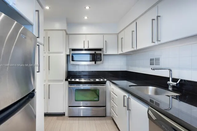 a kitchen with white cabinets and stainless steel appliances