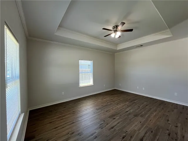 an empty room with wooden floor chandelier fan and windows