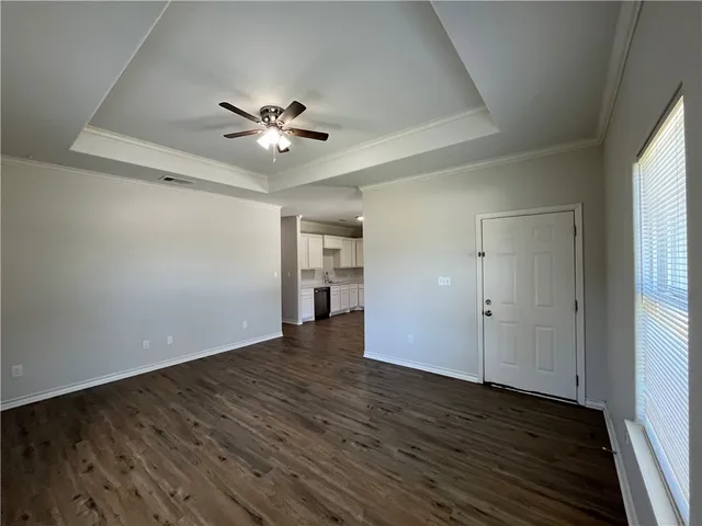 an empty room with wooden floor chandelier fan and windows