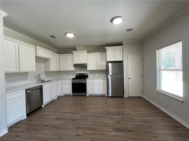 a kitchen with granite countertop a refrigerator and wooden cabinets