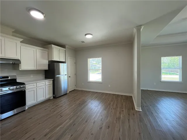 a kitchen with stainless steel appliances granite countertop a refrigerator a sink dishwasher a stove and white countertops with wooden floor