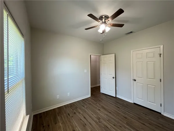 an empty room with wooden floor and windows