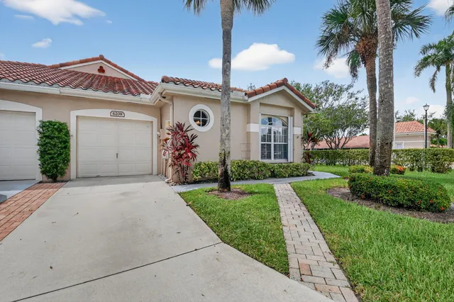 front view of a house with a yard and palm trees