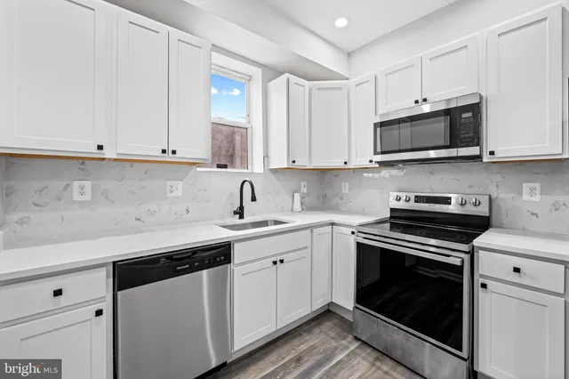 a kitchen with stainless steel appliances granite countertop grey cabinets a sink and a stove