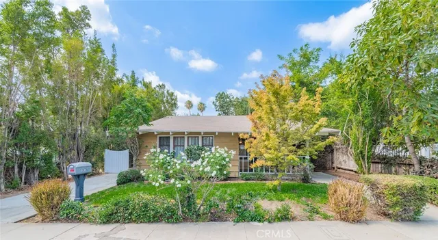 a front view of a house with a yard and trees