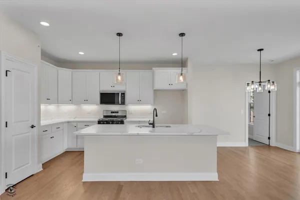 a large kitchen with stainless steel appliances granite countertop a sink a stove a refrigerator and island with wooden floor