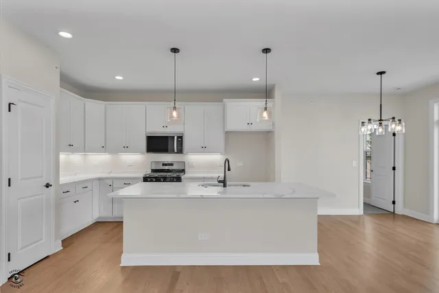 a large kitchen with stainless steel appliances granite countertop a sink a stove a refrigerator and island with wooden floor