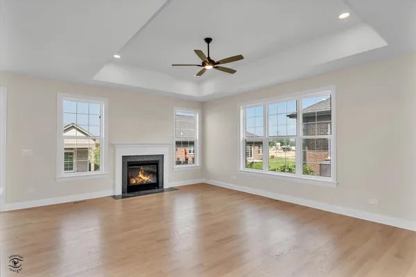 an empty room with windows fireplace and a ceiling fan