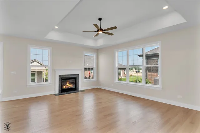 an empty room with windows fireplace and a ceiling fan