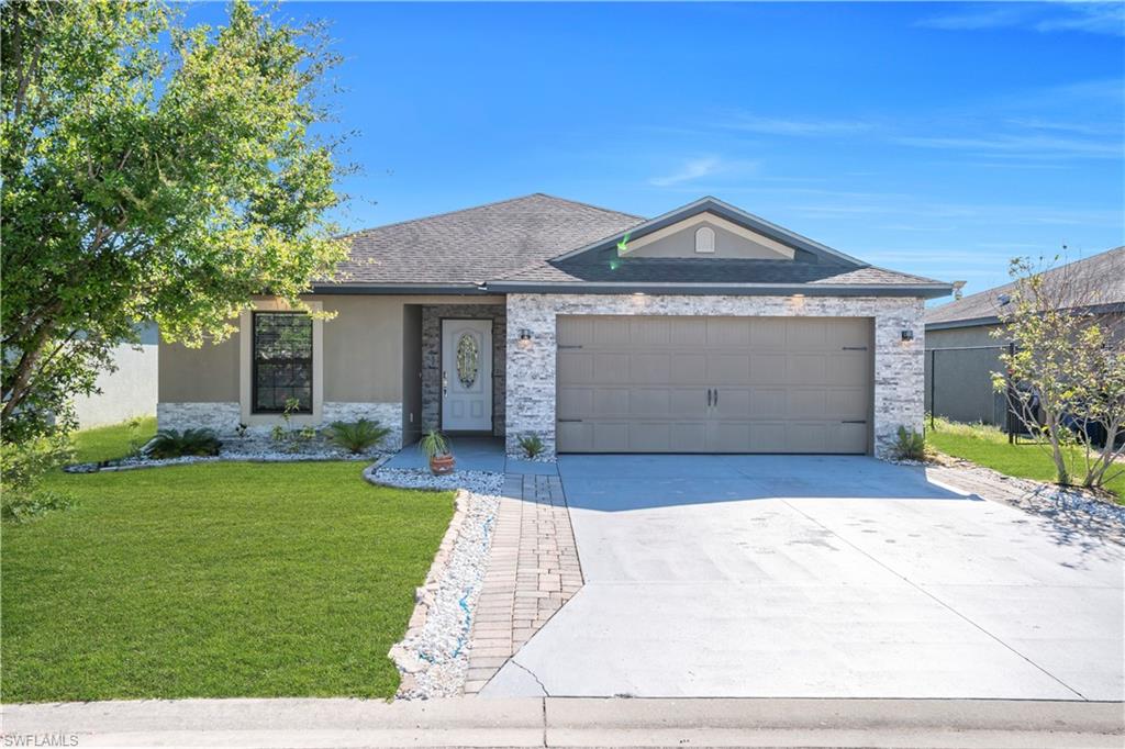 175 Shadowview Court Lehigh Acres, FL 33974 - Photo 2 of 39 a front view of a house with a yard and garage