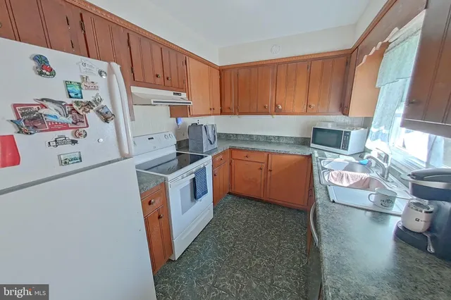 a view of a kitchen with fridge and wooden floor