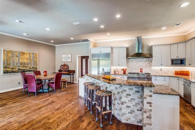 a kitchen with stainless steel appliances granite countertop a kitchen island a table and chairs in it
