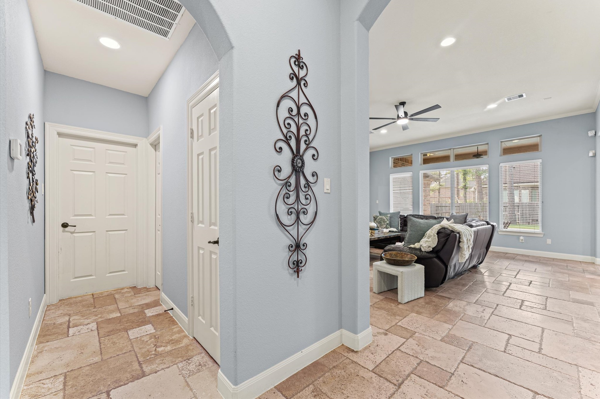 70 Valera Ridge Drive Spring, TX 77389 - Photo 31 of 37 Bright and welcoming entryway with light blue walls and decorative accents, leading to a spacious living area with large windows, a modern ceiling fan, and stylish tile flooring.