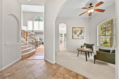 a view of a livingroom with a furniture a ceiling fan and window