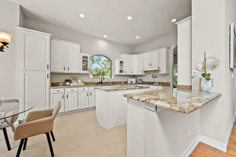 a kitchen with white cabinets and sink