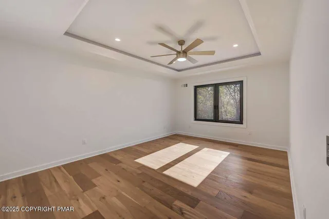 a view of a big room with wooden floor and windows