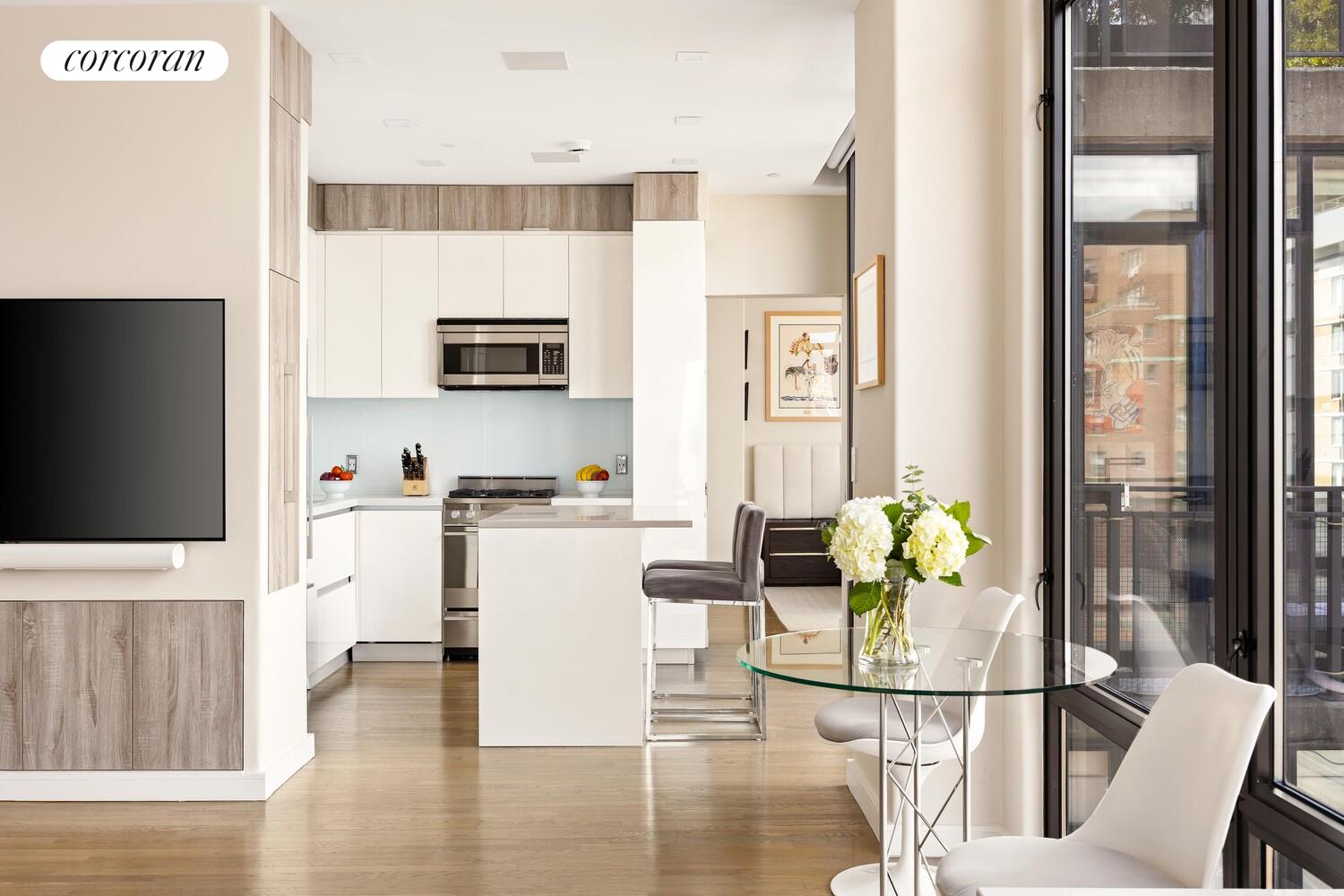 148 East 24th Street, Unit 15A Manhattan, NY 10010 - Photo 3 of 14 a kitchen with stainless steel appliances granite countertop a refrigerator a microwave a stove and white cabinets with wooden floor