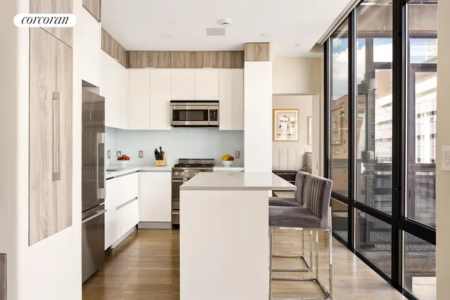 a kitchen with stainless steel appliances granite countertop a refrigerator a microwave a stove and white cabinets with wooden floor