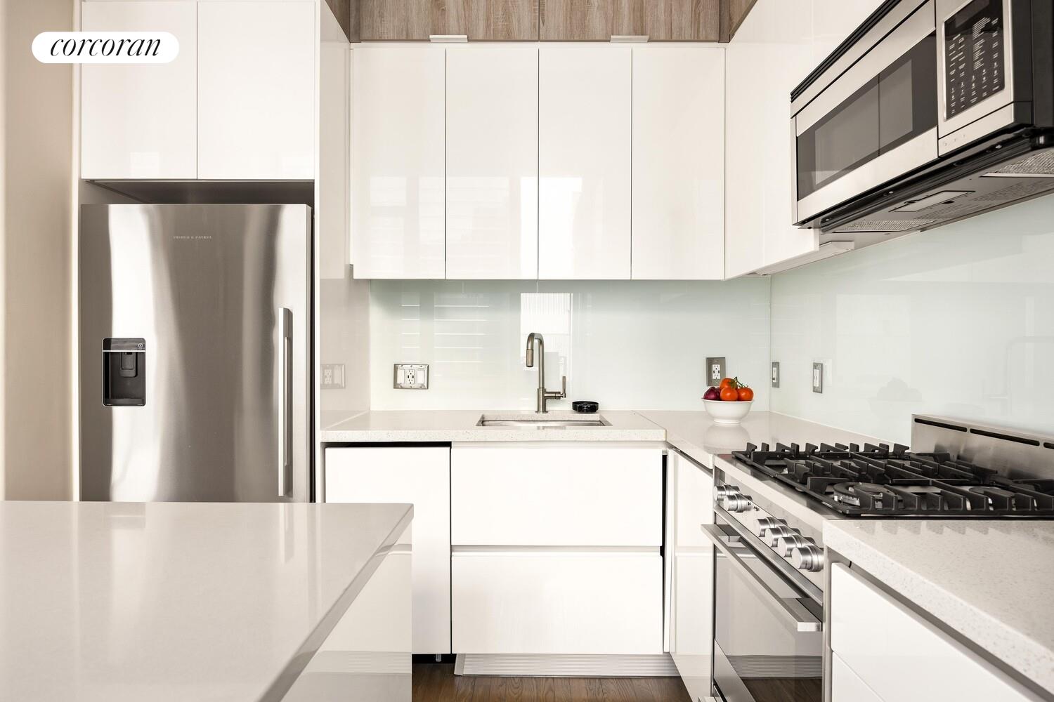 148 East 24th Street, Unit 15A Manhattan, NY 10010 - Photo 5 of 14 a kitchen with stainless steel appliances granite countertop a refrigerator sink stove and white cabinets