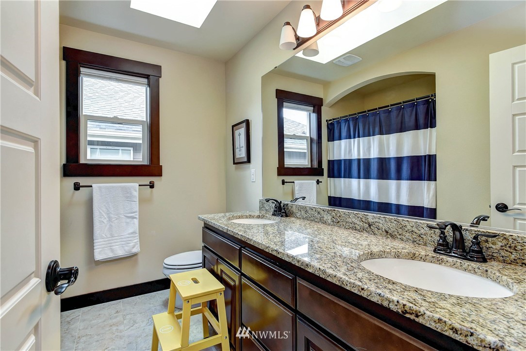 4410 220th Street Southeast Bothell, WA 98021 - Photo 25 of 28 a bathroom with a granite countertop sink a mirror and shower