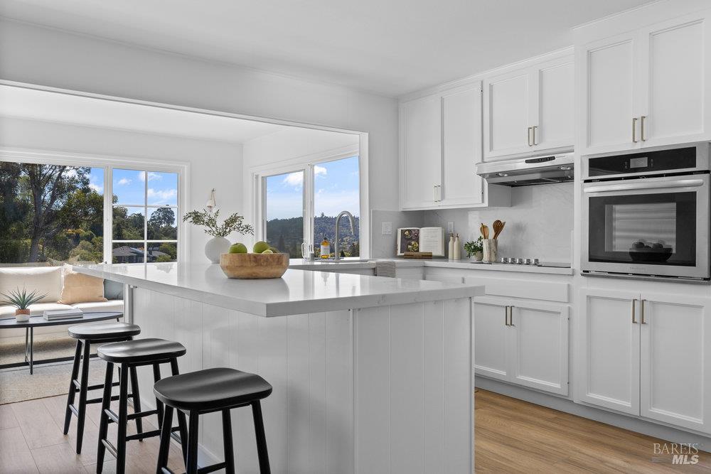 a kitchen with stainless steel appliances granite countertop a stove a sink dishwasher and white cabinets with wooden floor