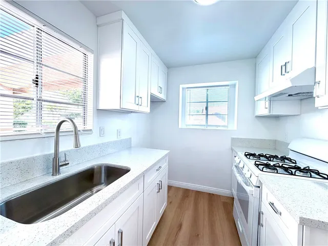 a kitchen with a sink a stove and cabinets